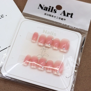 Pink gradient French press-on nails with rhinestones on a decorative card