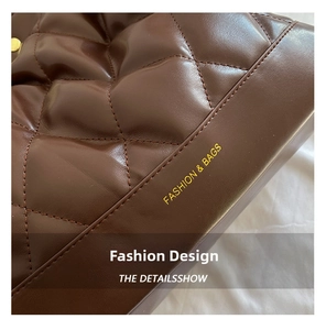 Detail of dark brown quilted leather with golden lettering on large shoulder bag