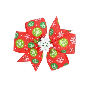 Detail of red Christmas ribbon bow clip with green snowflake pattern and center ornament