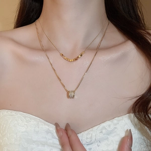 Close-up of double-layered 18k gold-plated necklace with a zircon cylinder pendant