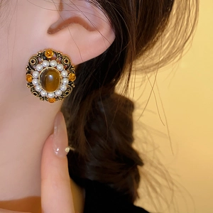 Close-up of vintage gold earring with amber stones and pearls worn on a female model
