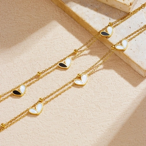 Gold-plated layered necklace with black and white heart charms and polished gold beads