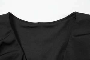 Détail de l'encolure en V et de la texture du tissu fin sur cette robe noire élégante