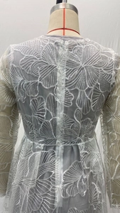 Detailed close-up of intricate lace floral embroidery and sequins on the evening gown back