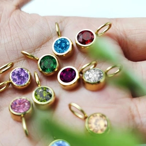 Macro view of colorful 8mm birthstone charms held in hand for scale and detail