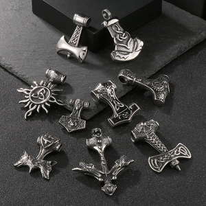 Macro view of silver Viking pendants including Mjolnir and wolf head on black stone