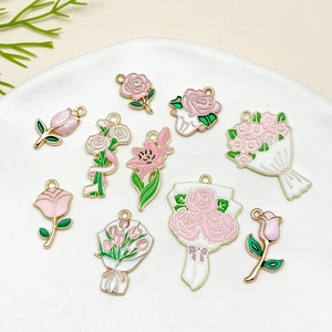 Detail of pink enamel flower charms including roses and tulips in a white ceramic dish