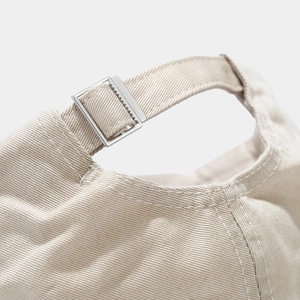 Detail of adjustable metal buckle and stitching on beige cotton baseball cap
