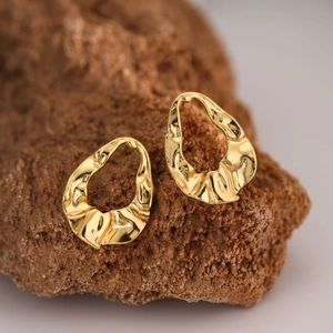 Minimalist gold butterfly irregular textured earrings on a natural stone base