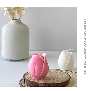 Detailed view of pink and white tulip shaped scented candles on a wooden slice base