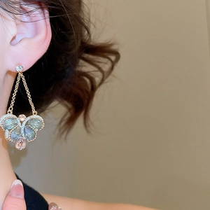 Close-up of vintage crystal drop earrings in pink and teal on a model with gold details