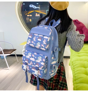 Detail of blue nylon backpack with unicorn patterns and white buckles on a female model