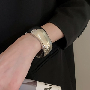 Close-up of a minimalist silver cuff bracelet with a polished mirror finish on a model