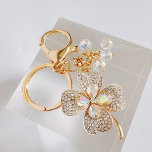 Sparkling clover keychain with colorful crystals and gold metal ring on a clear stand