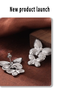 Detailed macro view of silver butterfly stud earrings with textured metallic finish