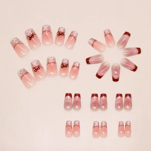 Close-up of pink cat-eye press-on nails with 3D bows, red french tips and dot patterns