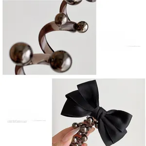 Detail of silk bow and spiral hair tie with metallic bead accents for women