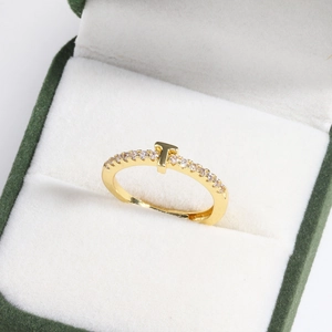 Macro detail of gold T-shape ring with sparkling pavé stones in a green velvet box