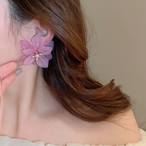 Close-up of pink translucent floral earrings with gold center and small pearl accent