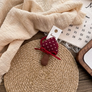 Close-up of a handmade red mushroom hair tie with white polka dots on a rustic background