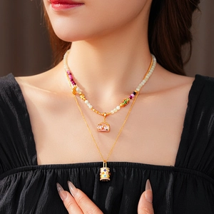 Close-up of stacked vintage enamel bead necklaces with flower basket and lock pendants