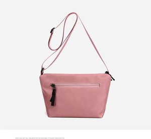 Detailed macro view of pink nylon crossbody bag with smooth texture and zipper pockets