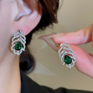 Gros plan de boucles d'oreilles feuilles en argent avec cristaux gouttes vert émeraude
