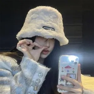 Détail d'un chapeau bob en peluche blanche montrant la texture en fausse fourrure et l'étiquette
