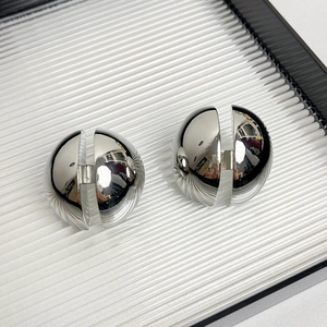 Vue macro de boucles d'oreilles demi-sphères argentées avec finition miroir polie