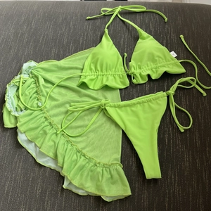 Dettaglio flat lay del bikini 3 pezzi verde neon con gonna a volant in mesh e taglia S