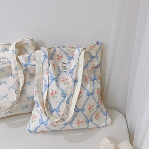 Detail of light blue bow floral canvas tote bag featuring rose patterns and a woven label