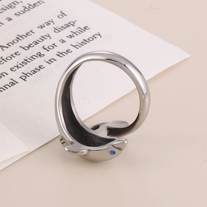 Detailed view of silver dolphin ring with blue sapphire eye on paper background