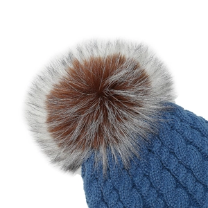 Detail of blue cable knit hat showing textured weave and fluffy dual-color pom-pom topper