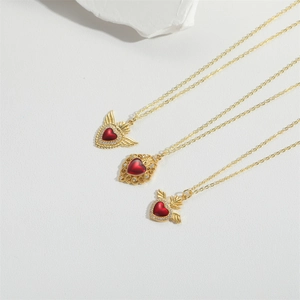Elegant gold plated necklaces with deep red zircon heart pendants on white textured stone