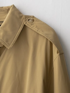 Détails du trench-coat kaki montrant le tissu sergé et les pattes d'épaulette