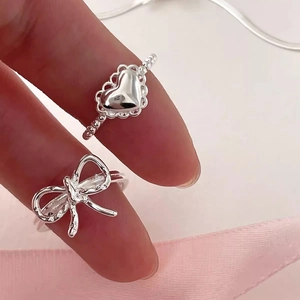 S925 sterling silver heart and bow open rings displayed on hand against soft background