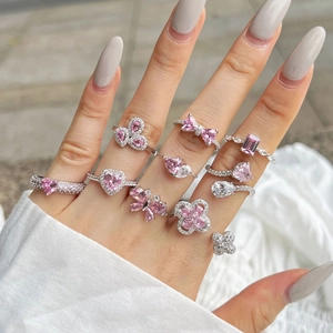 Detailed view of silver rings featuring pink heart and butterfly crystal accents on hand