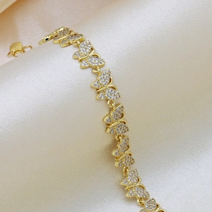 Gold plated butterfly bracelet with sparkling cubic zirconia on champagne silk backdrop