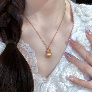 Elegante Halskette mit goldenem Glücksbeutel-Anhänger an einer feinen Kette auf Spitze