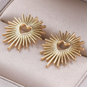 Detailed close-up of sunburst gold earrings with a hollow heart center on jewelry box