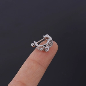 Macro detail of silver cartilage stud with pavé cubic zirconia on the fingertips