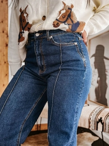 Detail van high-waist denim broek met voornaad ontwerp en verticale stiksels op de stof