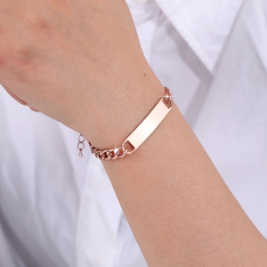 Detailed view of rose gold stainless steel ID bracelet with Cuban link chain on wrist