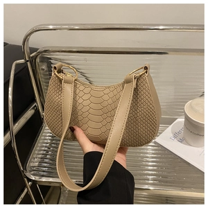 Detail of khaki faux crocodile texture on a crescent shoulder bag with metal rings