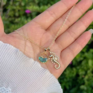 Macro view of 18K gold seahorse pendant with sparkling zircons and blue ocean stone