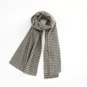 Detailed view of the black and white houndstooth scarf texture with tassel fringe edges