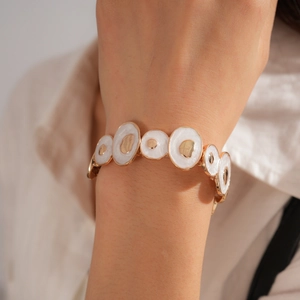 Gros plan d'un bracelet élastique de style bohème en or et émail porté par un mannequin