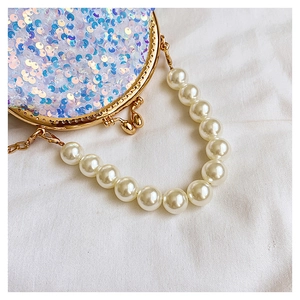 Detail of blue-purple sequin crossbody bag with pearl handle and golden frame