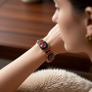 Vista macro dettagliata del bracciale dorato vintage con maglie verdi e perle rosse