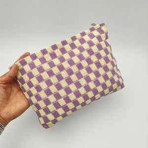Handheld view of a large checkerboard knit makeup bag in purple and yellow colors